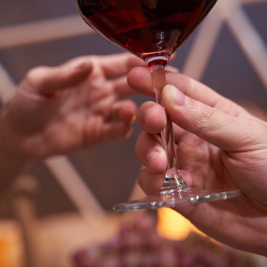 Person holding glass of wine by its stem and passing it to female in restaurant